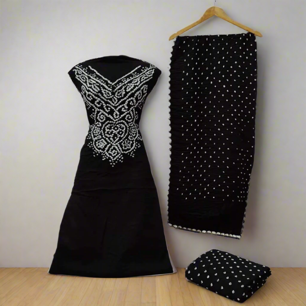 Black bandhani dress material with on a hanger against a decorative tiled wall.