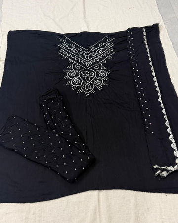 Black fabric with white embroidery on a beige surface