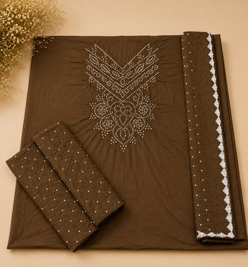 A dark brown fabric set laid flat on a beige background, featuring a large embroidered neckline motif, matching fabric pieces, and a decorative border with white scalloped trim.