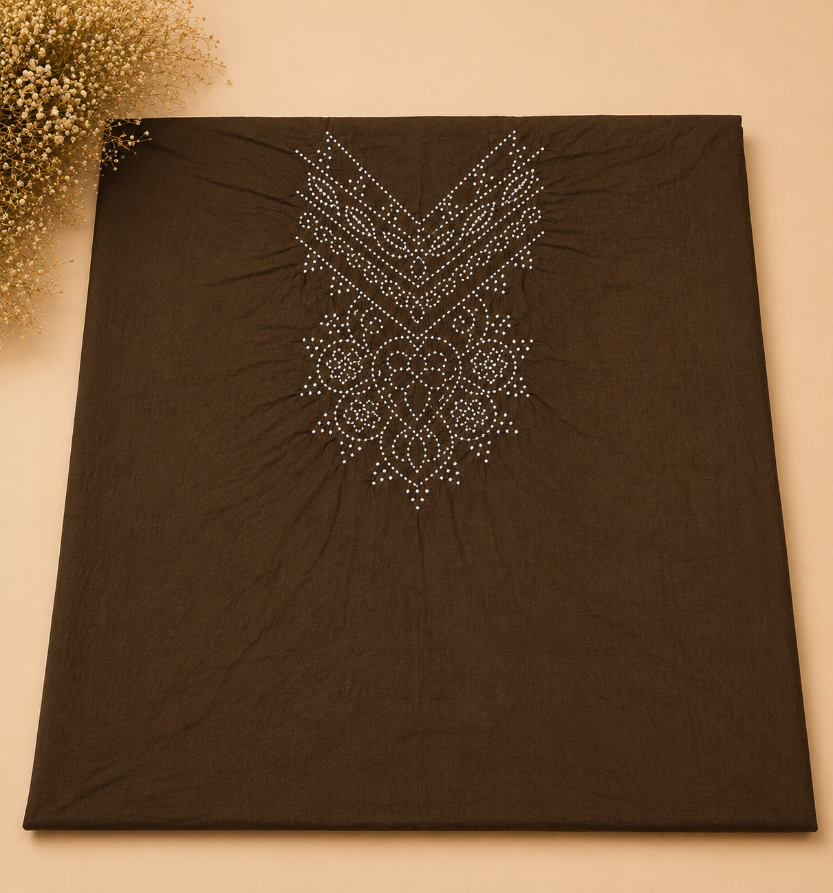 A square dark brown fabric item, likely a scarf or shawl, featuring a silver rhinestone or bead geometric and floral pattern on the upper half. The fabric is laid flat on a beige background with dried flowers in the top-left corner.