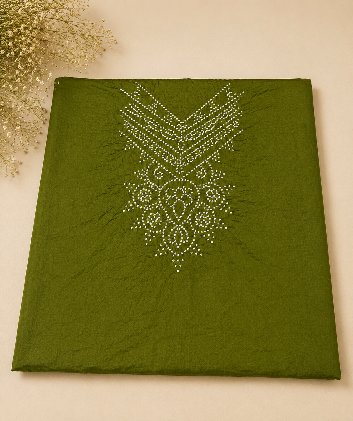 An olive green fabric garment, likely a kurta or dress, laid flat on a beige background. The fabric features a white embroidered or printed geometric and floral mandala pattern on the front.