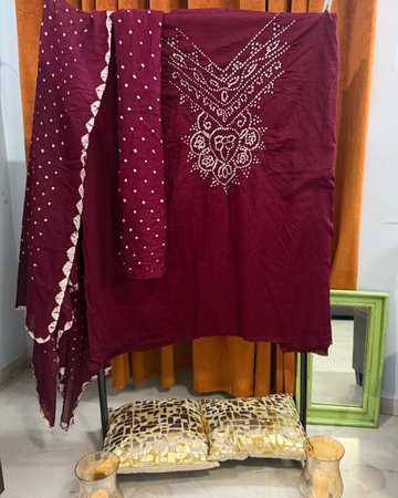 Maroon Bandhani fabric draped over a chair with a mirror in the background