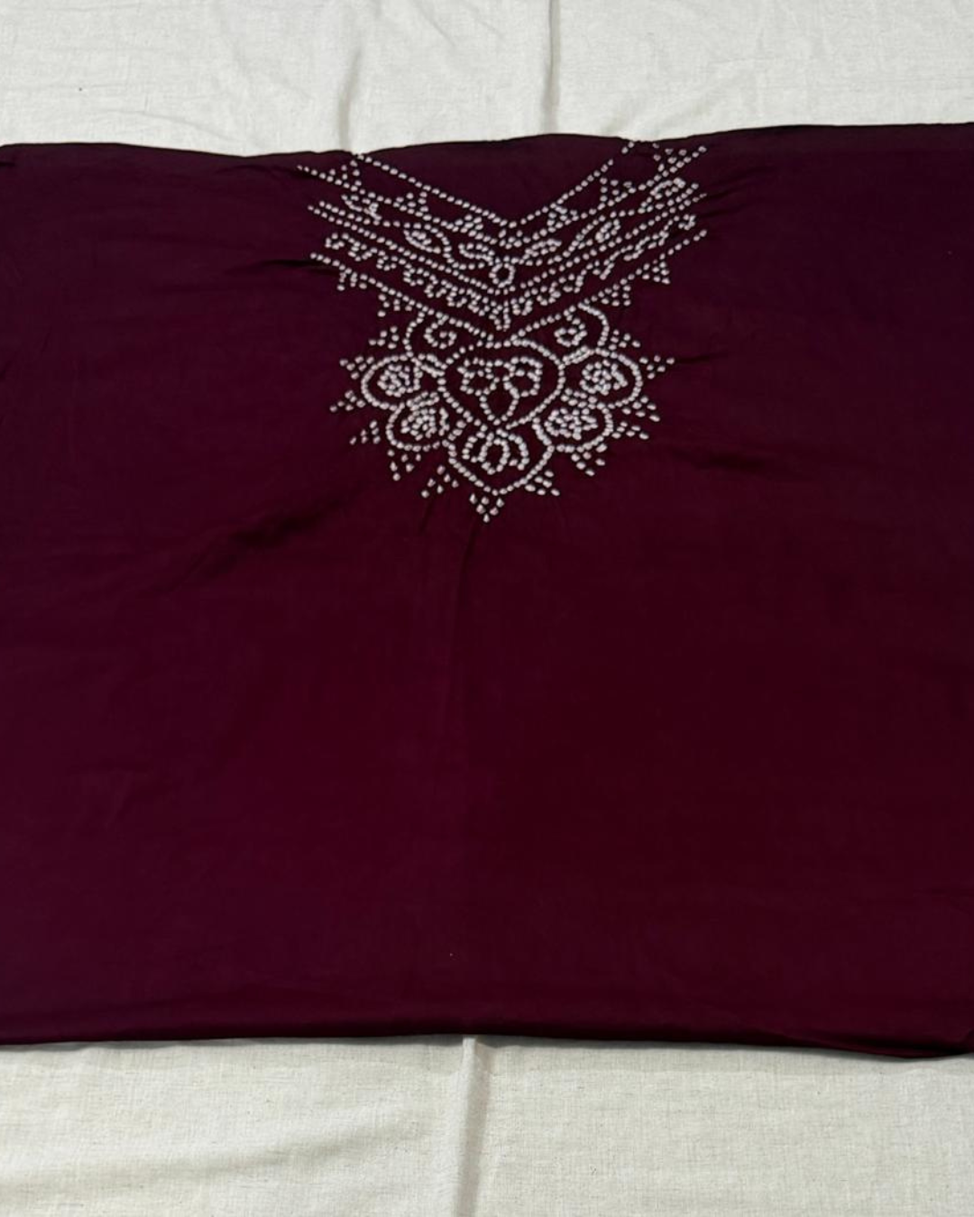 Maroon bandhani  fabric on a light gray background