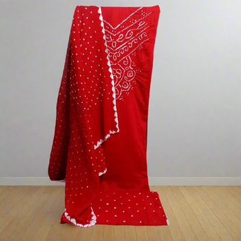 Red Bandhani suit fabric with draped over a chair against a plain wall.