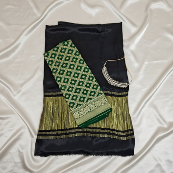 flat lay black saree with green bandhani blouse piece on top with off white satin backgrond