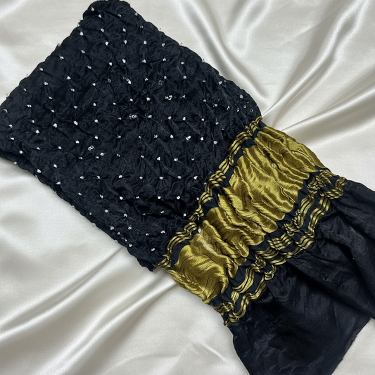 flat lay of black bandhani blouse piece on off white satin background