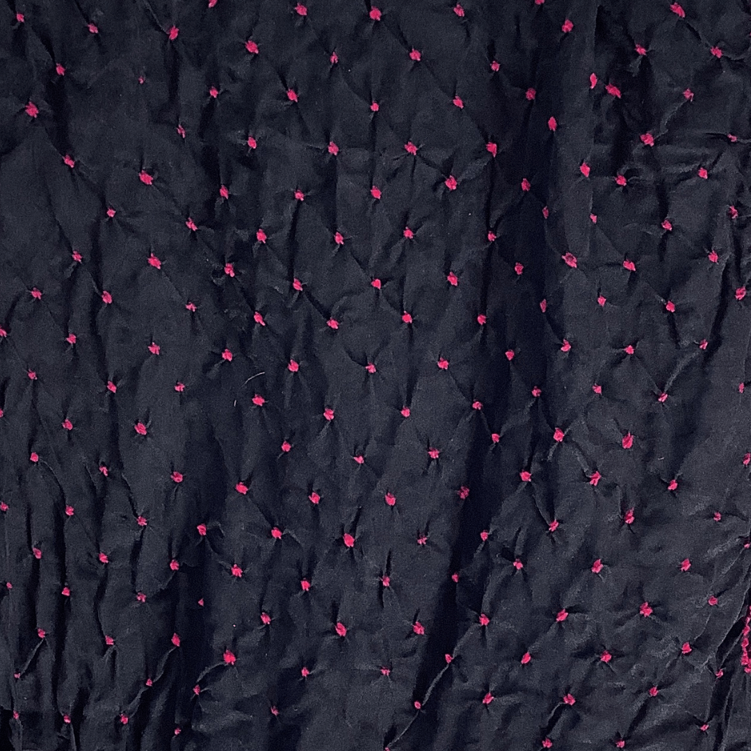 close up of pink bandhani on black fabric