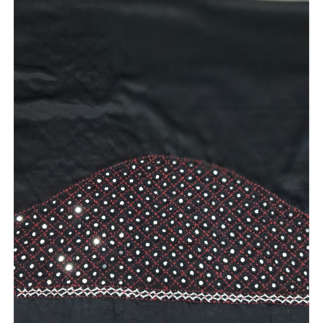 Close-up of a black fabric garment or textile with a curved section heavily embellished with small white and silver reflective dots, red stitched lines, and a white zigzag border.