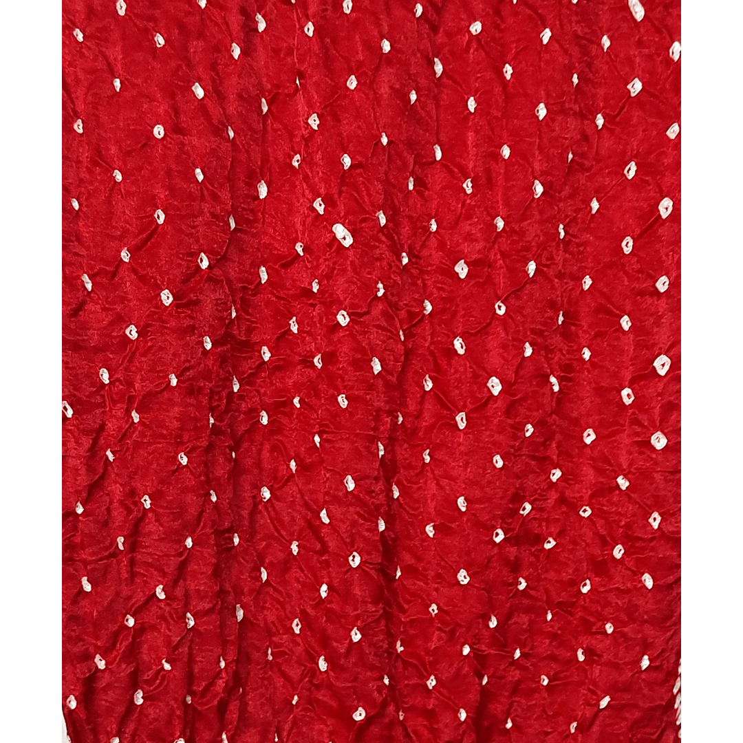 close up of white bandhej on maroon fabric