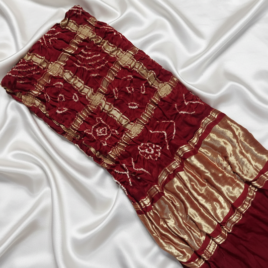Maroon gharchola bandhani blouse piece flat lay on off white satin background