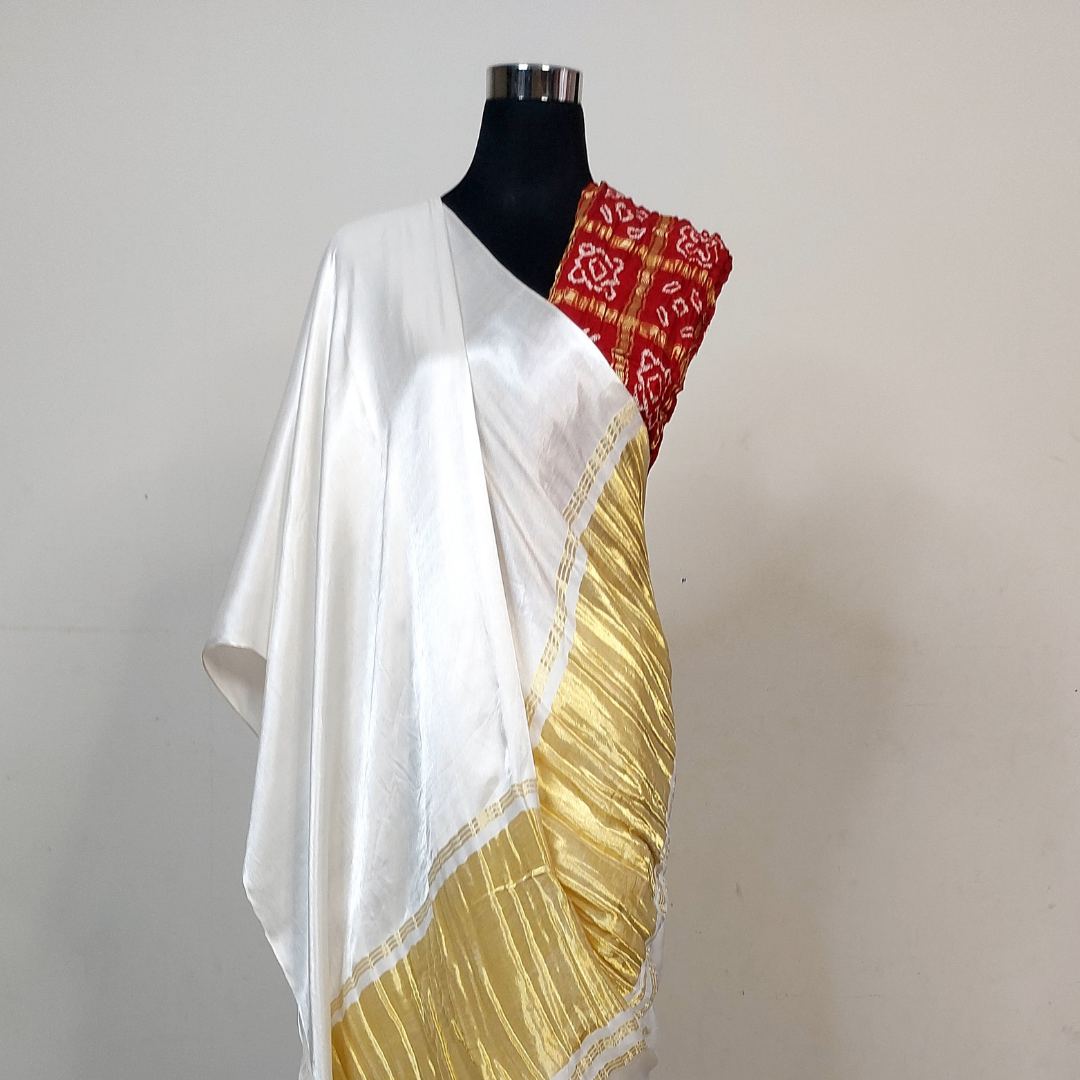 White saree with gold border on a mannequin against a plain background
