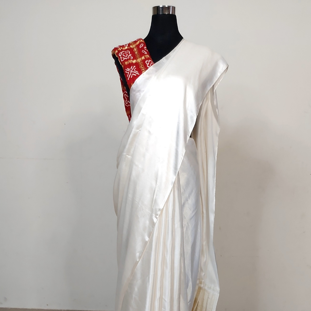 White saree with a red and gold border on a mannequin against a white background