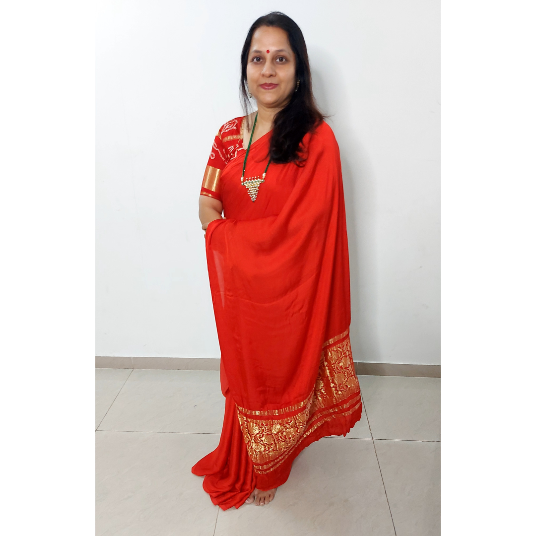 Woman wearing a red saree with golden lagadi patta patterns against a white background