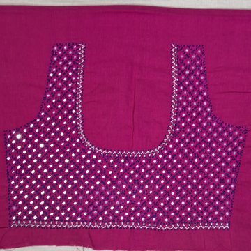 A magenta pink blouse piece with a U-neckline, heavily decorated with silver mirror work and sequins in a dotted pattern, laid flat on a white surface.