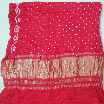 close up of pure gajji silk white dana bandhej on tomato red fabric 