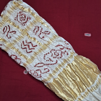 close up of Red bandjej on white Gajji silk gharchola blouse piece flat lay on red background
