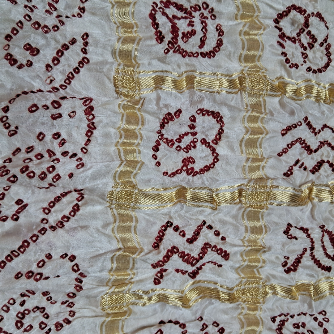 close up of red bandhej on white gharchola blouse piece