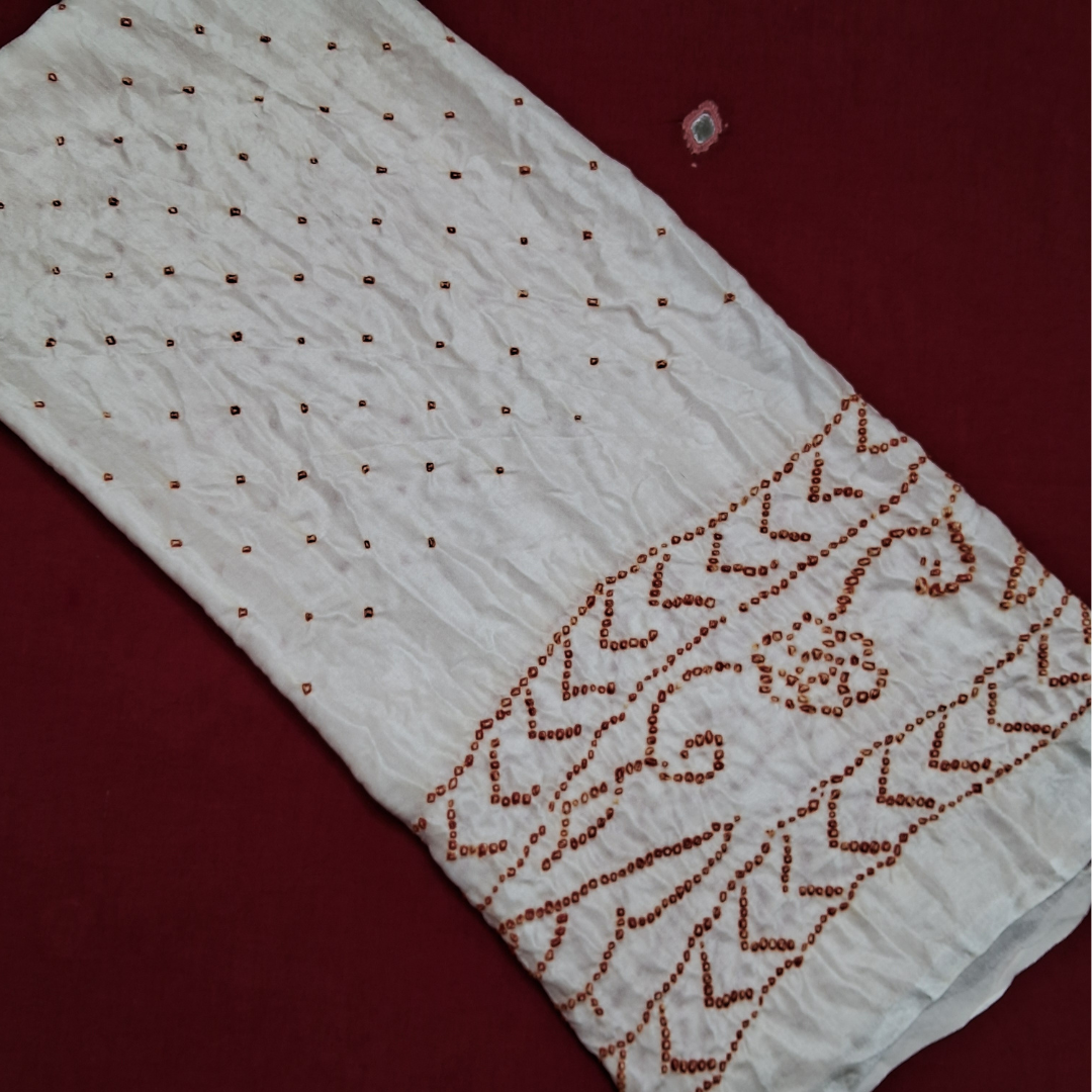 red bandhej on pure gajji silk white fabric on a red background
