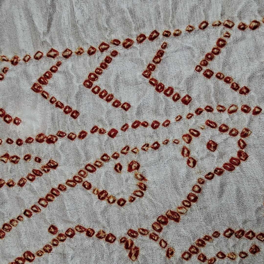 close up of red bandhani on white pure gajji silk blouse piece