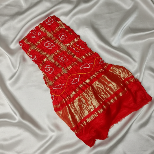 red gharchola bandhani blouse piece flat lay on off white satin background