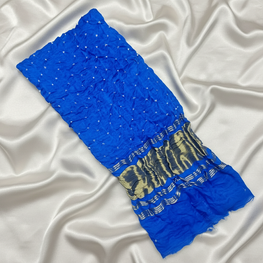 flat lay of royal blue bandhani blouse piece on off white satin background