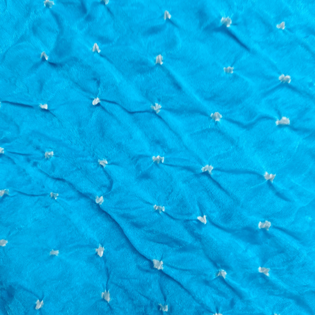 close up of white dana bandhani on sky blue fabric