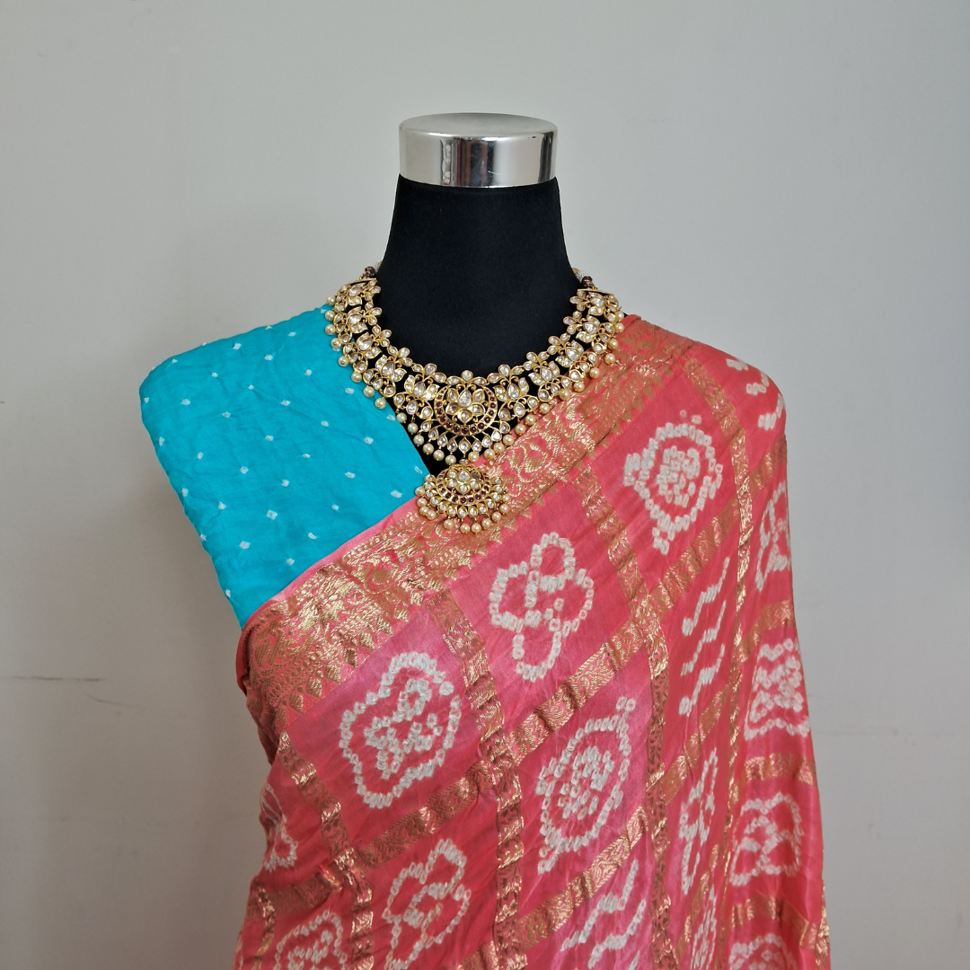 Mannequin wearing a pink gajji silk gharchola bandhani saree with gold patterns and a blue blouse
