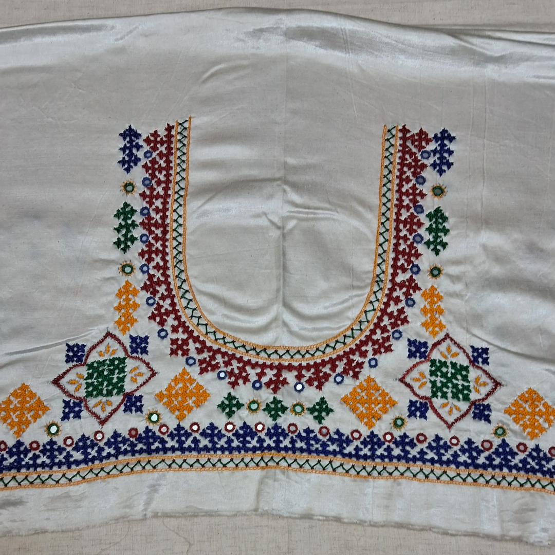 An embroidered off-white blouse yoke or neckline featuring a U-shaped collar and geometric diamond motifs in red, blue, green, and orange with small mirror work accents.