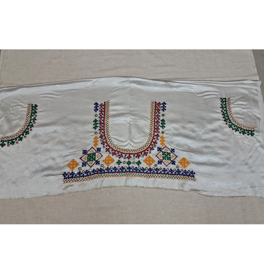 A white embroidered blouse or sari panel featuring traditional multicolor cross-stitch patterns in red, green, blue, and yellow on a beige fabric background.