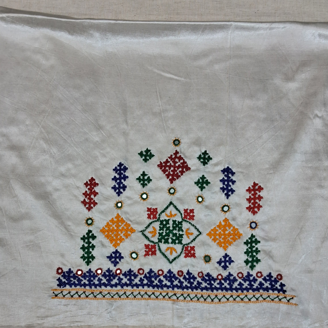 A square white embroidered textile, likely a Ukrainian or Slavic handkerchief or napkin, featuring a colorful geometric cross-stitch pattern with red, green, blue, orange, and yellow motifs on a white fabric background.