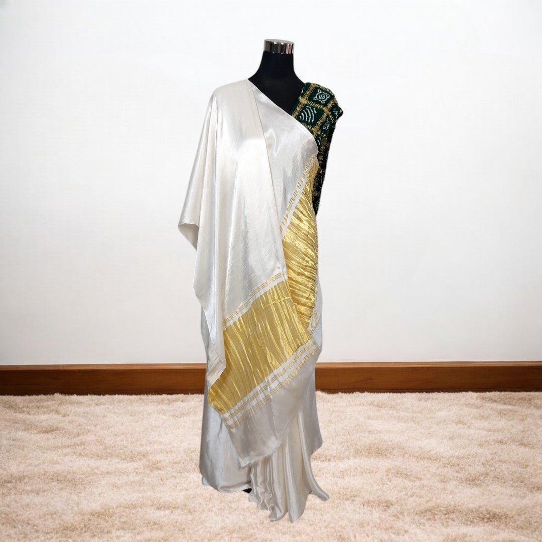 White saree with gold border on a mannequin against a white background