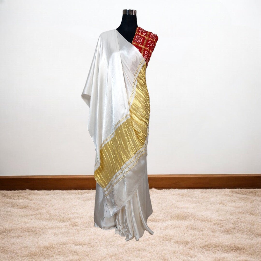 White saree with gold border draped over a mannequin against a white background