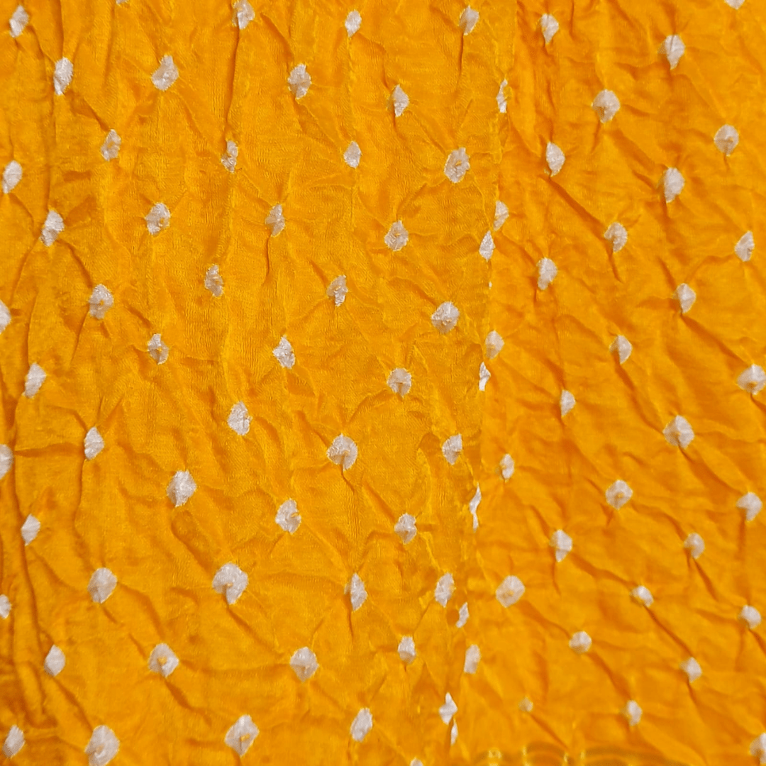 close of white dana bandhej on yellow fabric